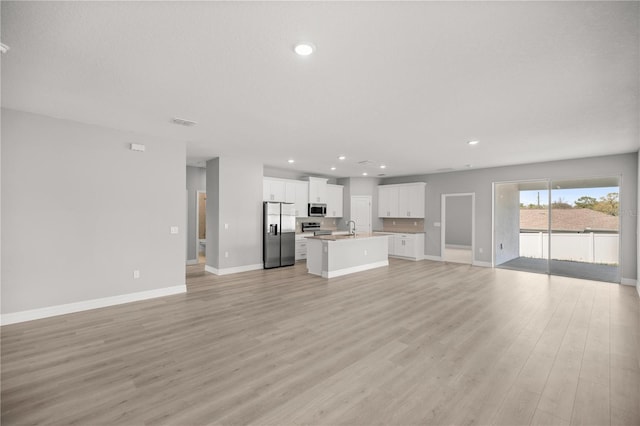 unfurnished living room featuring a sink, baseboards, visible vents, light wood-style floors, and recessed lighting