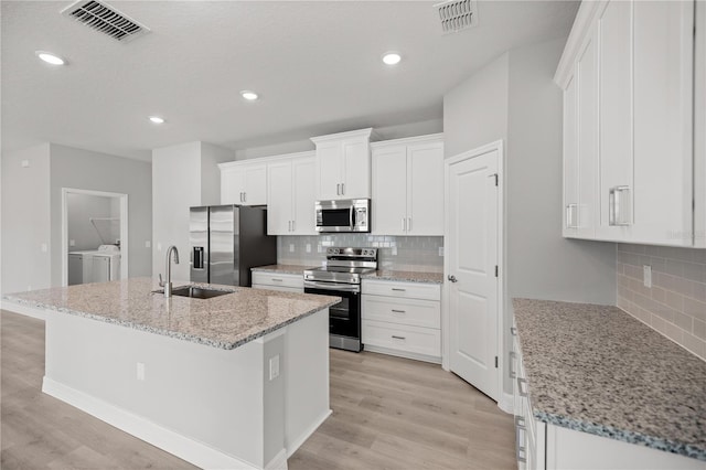 kitchen with a sink, stainless steel appliances, washing machine and dryer, and visible vents