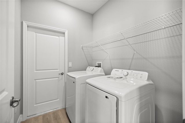 clothes washing area featuring washing machine and clothes dryer, laundry area, and light wood-style floors