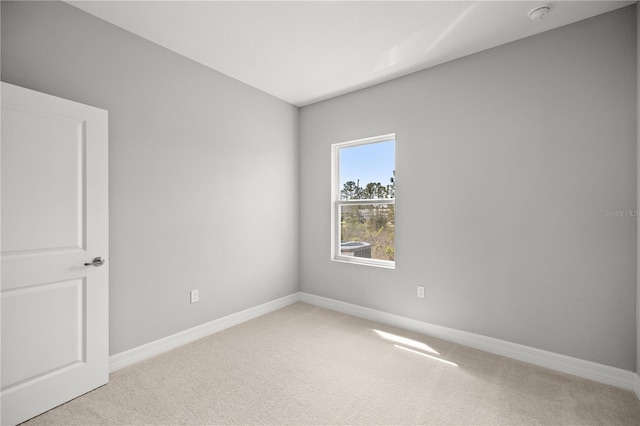 carpeted empty room featuring baseboards