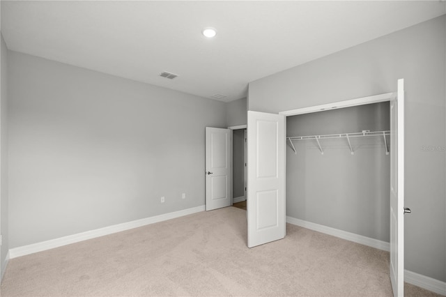 unfurnished bedroom featuring baseboards, visible vents, a closet, and light colored carpet