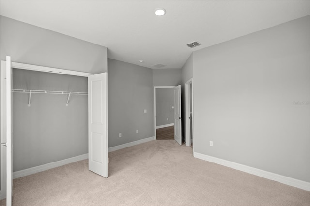 unfurnished bedroom featuring a closet, baseboards, light colored carpet, and visible vents