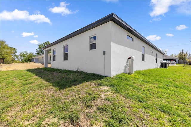 view of home's exterior featuring stucco siding, central AC, and a yard