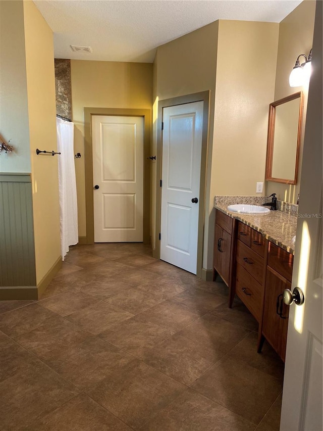 bathroom featuring visible vents, a shower with curtain, a wainscoted wall, and vanity