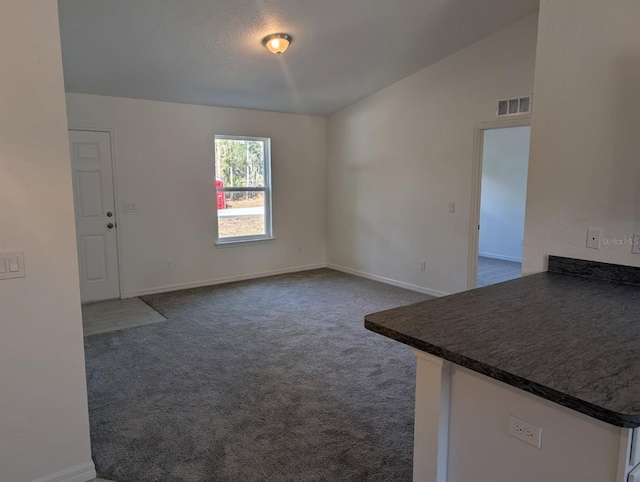 unfurnished living room with lofted ceiling, baseboards, visible vents, and dark carpet