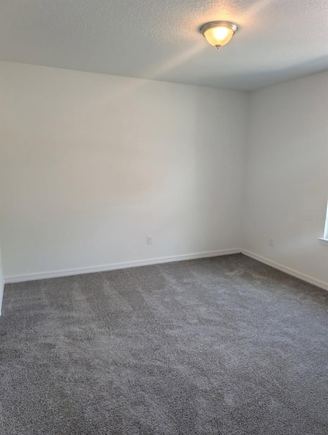 unfurnished room featuring baseboards, a textured ceiling, and dark carpet