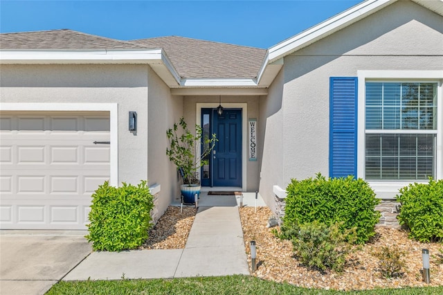 doorway to property with stucco siding, an attached garage, and roof with shingles