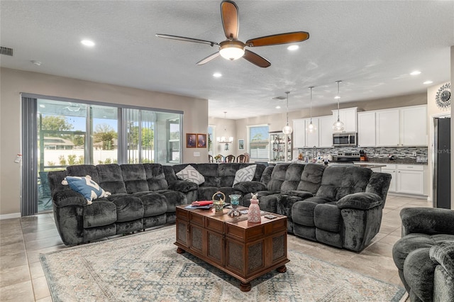 living room featuring recessed lighting, a textured ceiling, and ceiling fan with notable chandelier