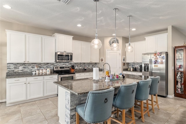 kitchen featuring a breakfast bar, white cabinets, tasteful backsplash, and stainless steel appliances