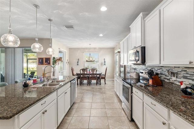 kitchen with a sink, plenty of natural light, backsplash, stainless steel appliances, and light tile patterned floors