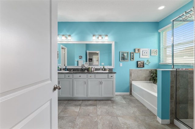 bathroom featuring a garden tub, double vanity, a shower with door, and a sink