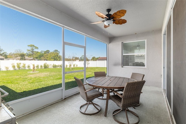 sunroom with ceiling fan and a water view