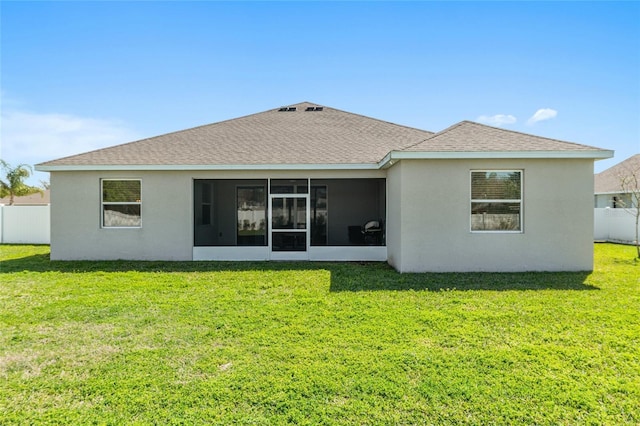 back of house featuring a lawn, a shingled roof, fence, and stucco siding