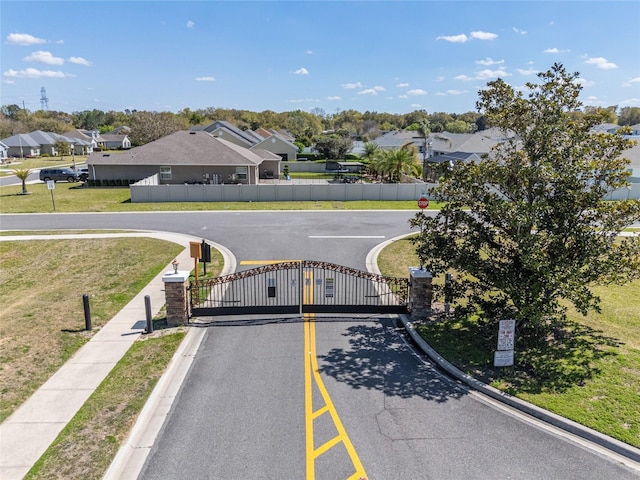 view of street with a gated entry, a residential view, traffic signs, and a gate