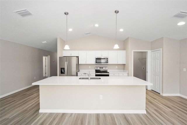 kitchen featuring visible vents, a sink, stainless steel appliances, white cabinets, and a large island with sink