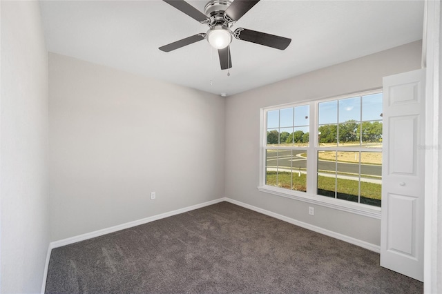 empty room with dark colored carpet, baseboards, and a ceiling fan