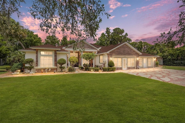 single story home with concrete driveway, a yard, brick siding, and a garage