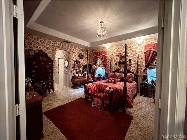 carpeted bedroom featuring visible vents, a tray ceiling, a textured ceiling, wallpapered walls, and a chandelier