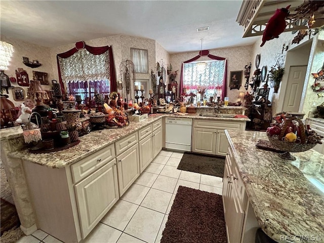 kitchen with light tile patterned floors, visible vents, wallpapered walls, white dishwasher, and a sink