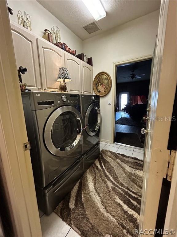 washroom featuring visible vents, cabinet space, separate washer and dryer, and light tile patterned flooring