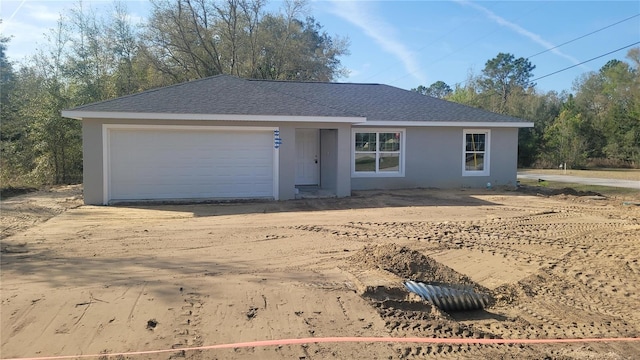 single story home featuring an attached garage, driveway, roof with shingles, and stucco siding