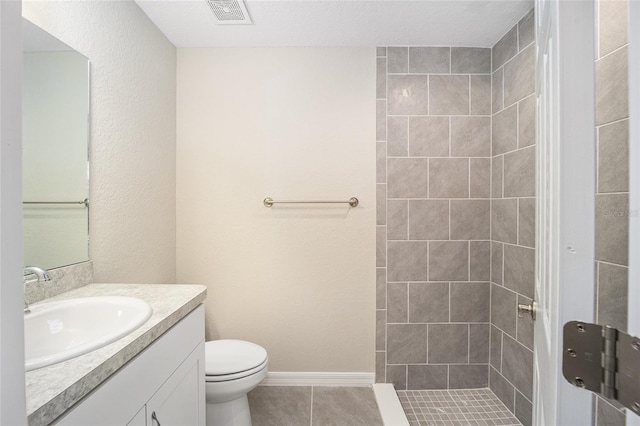 full bathroom with tile patterned floors, visible vents, toilet, tiled shower, and vanity