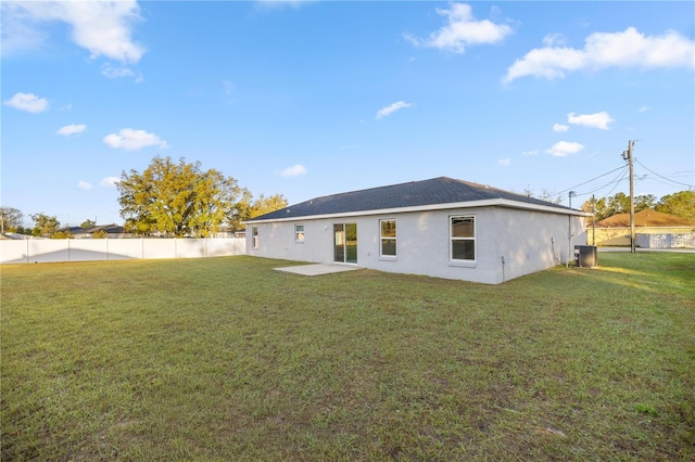 rear view of property with stucco siding, a lawn, and fence