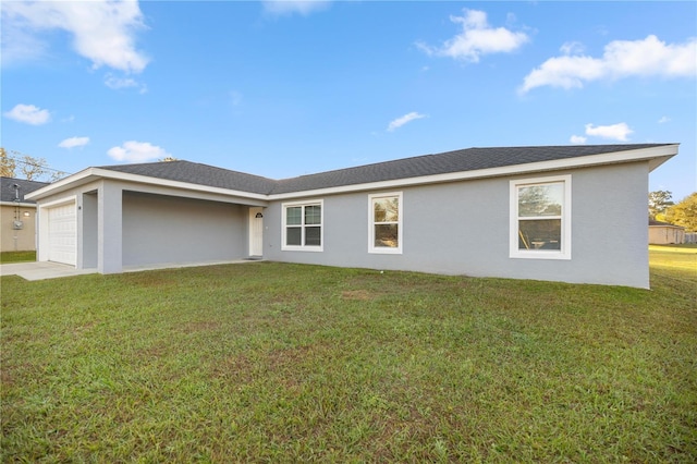 back of property featuring a garage, a yard, and stucco siding