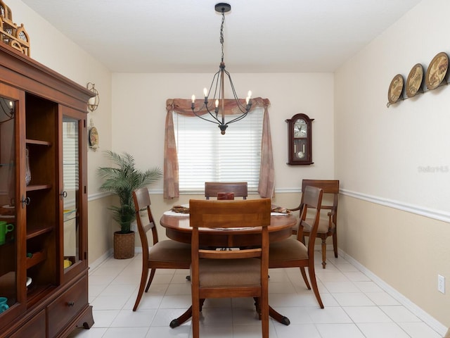 dining space featuring light tile patterned floors, baseboards, and an inviting chandelier