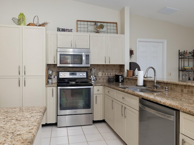 kitchen with lofted ceiling, backsplash, appliances with stainless steel finishes, and a sink