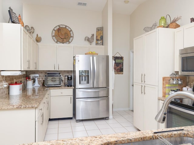 kitchen with visible vents, backsplash, appliances with stainless steel finishes, light tile patterned flooring, and white cabinetry