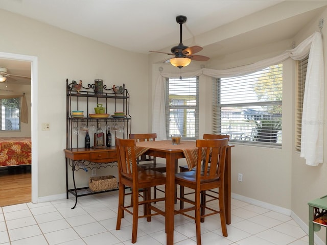 dining space with light tile patterned floors, baseboards, and a ceiling fan