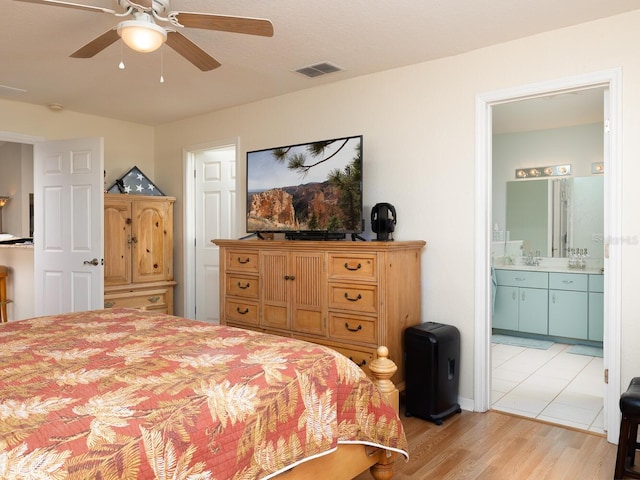 bedroom with visible vents, a sink, connected bathroom, light wood finished floors, and ceiling fan