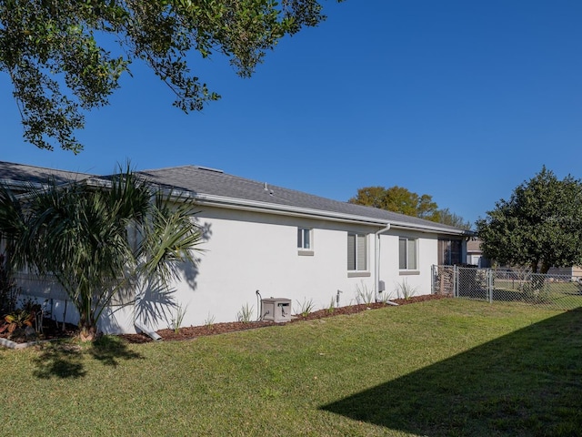 back of property featuring stucco siding, a lawn, and fence