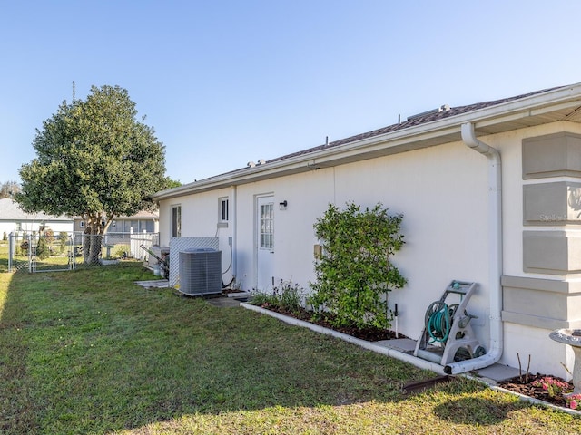 view of home's exterior featuring a yard, central AC unit, and fence