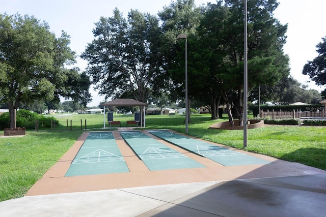 view of home's community featuring shuffleboard, a lawn, and fence