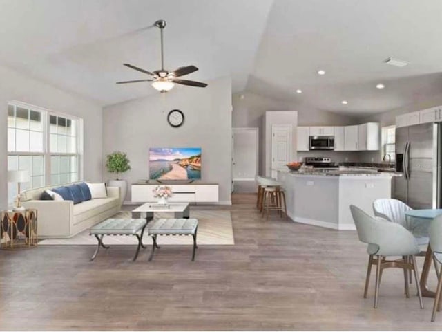 living room with light wood-style floors, a healthy amount of sunlight, and ceiling fan