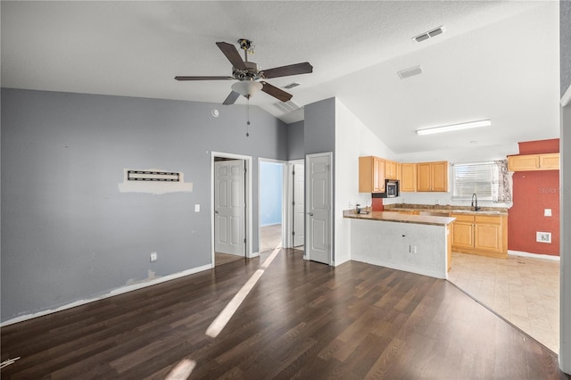 kitchen with visible vents, light brown cabinetry, a peninsula, a ceiling fan, and a sink