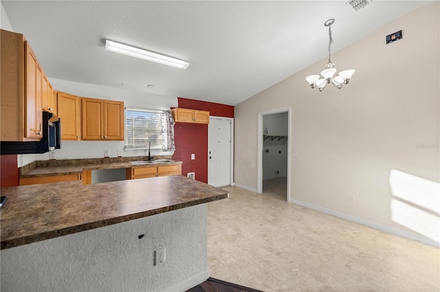 kitchen with dark countertops, vaulted ceiling, an inviting chandelier, hanging light fixtures, and a sink