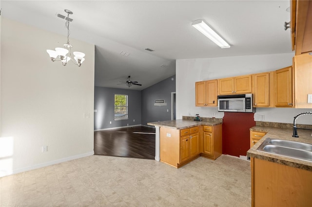 kitchen with a sink, stainless steel microwave, dark countertops, open floor plan, and light floors