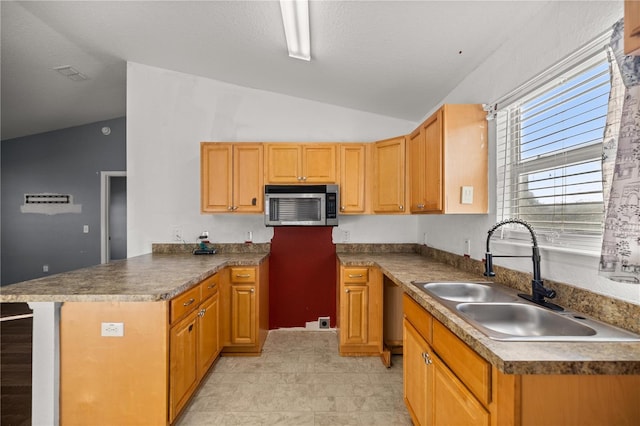 kitchen with visible vents, a sink, stainless steel microwave, a peninsula, and vaulted ceiling