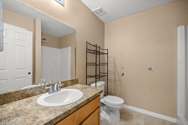 bathroom featuring visible vents, baseboards, toilet, vanity, and a textured ceiling