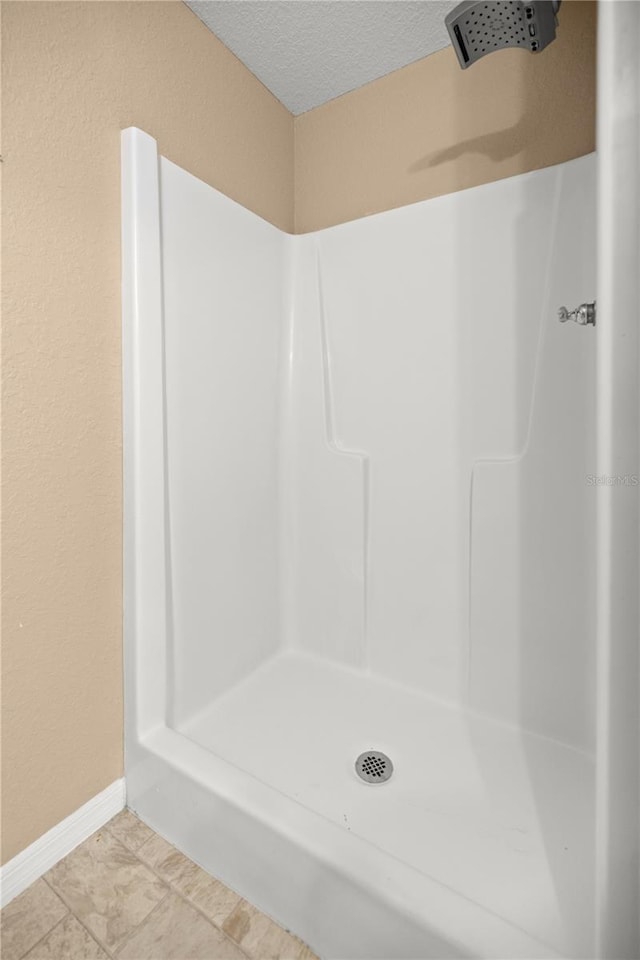 bathroom featuring a shower stall, a textured ceiling, and baseboards