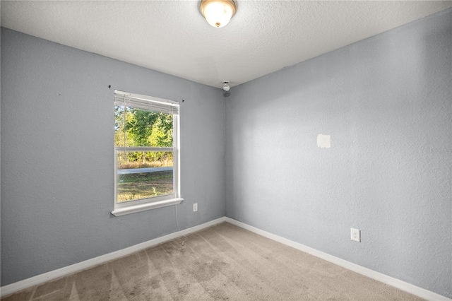 spare room with a textured wall, a textured ceiling, baseboards, and carpet floors