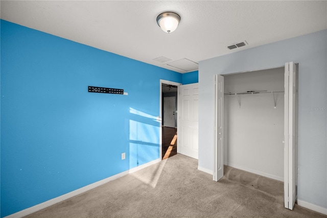 unfurnished bedroom with visible vents, baseboards, attic access, carpet floors, and a closet