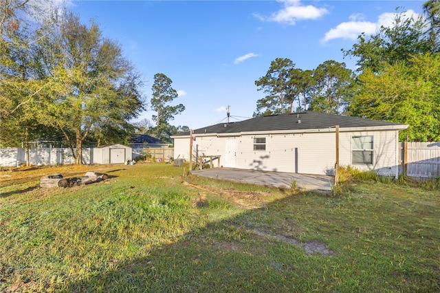 back of house featuring a patio area, a lawn, a storage shed, a fenced backyard, and an outbuilding