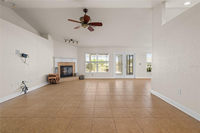 unfurnished living room with a ceiling fan, baseboards, high vaulted ceiling, light tile patterned flooring, and a tiled fireplace