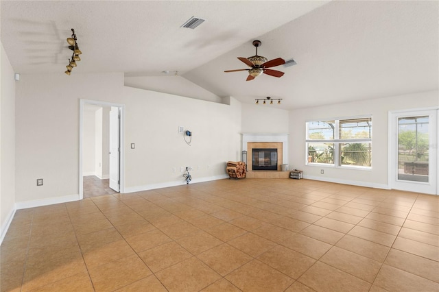 unfurnished living room featuring light tile patterned flooring, ceiling fan, a fireplace, and vaulted ceiling