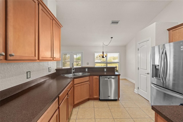 kitchen with a peninsula, an inviting chandelier, light tile patterned flooring, a sink, and stainless steel appliances