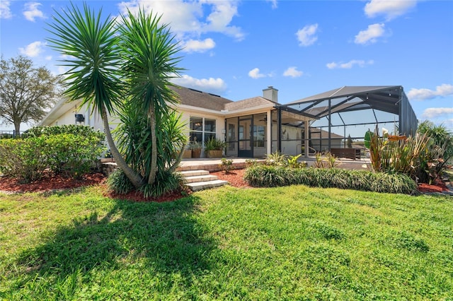 rear view of house featuring a lanai, a chimney, and a yard